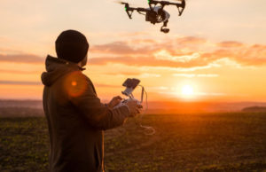 Un homme pilotant un drone au coucher de soleil