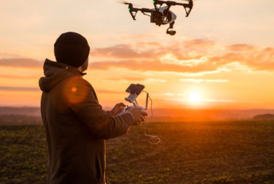 Un homme pilotant un drone au coucher de soleil